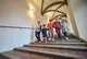 Fünf Kinder gehen Hand in Hand eine weite Treppe hinunter.