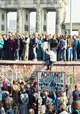 Viele Menschen drängen sich auf und vor der Berliner Mauer.